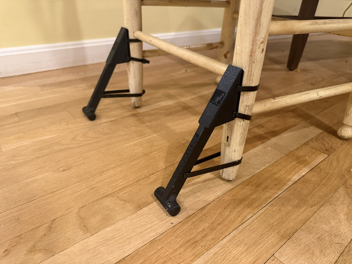 Pair of Jackaroo Leg anti-tip chair stabilizers strapped to the back legs of a wooden kitchen chair